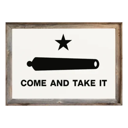 Framed “Come and Take It” flag with black star, cannon, and text on white field, set in rustic light‑wood frame