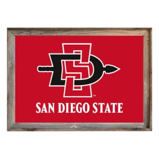 A framed sign with a bright red background displays the interlocking black letters "SD" with a white outline, forming the logo for San Diego State University. Below the logo, in bold white capital letters, are the words "SAN DIEGO STATE". The frame is rustic, appearing to be made of weathered gray wood.