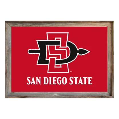 A framed sign with a bright red background displays the interlocking black letters "SD" with a white outline, forming the logo for San Diego State University. Below the logo, in bold white capital letters, are the words "SAN DIEGO STATE". The frame is rustic, appearing to be made of weathered gray wood.